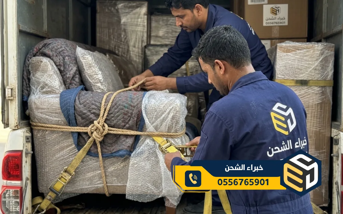 فريق عمل مدرب يقوم بتحميل قطع الأثاث الكبيرة والمغلفة إلى شاحنة نقل في الرياض